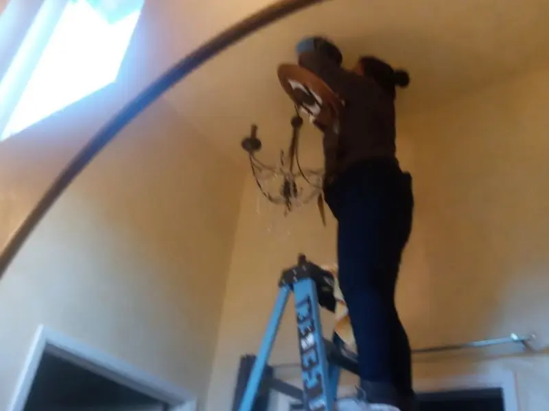 Electrician installing a chandelier in a Kuna residence